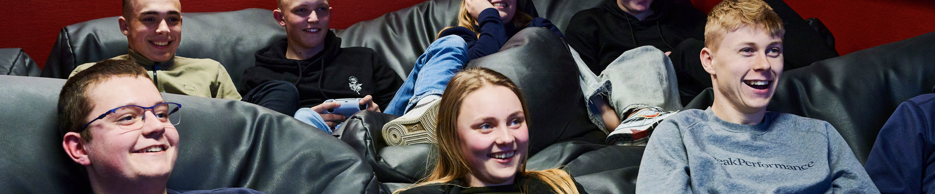 7 unge mennesker der ligger i sækkestole, to spiller playstation