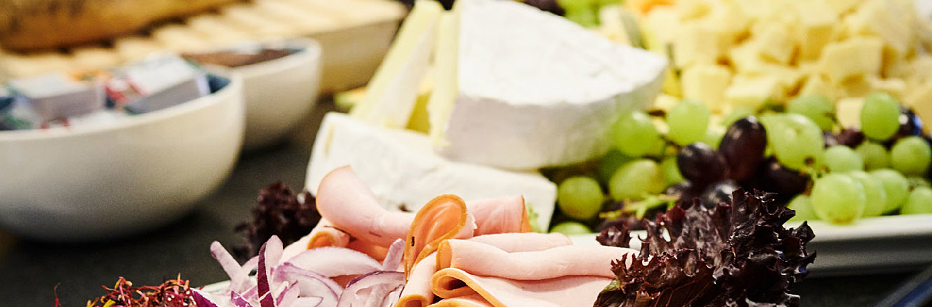 Et billede af frokosten. Der er vindruer, noget ost og pålæg